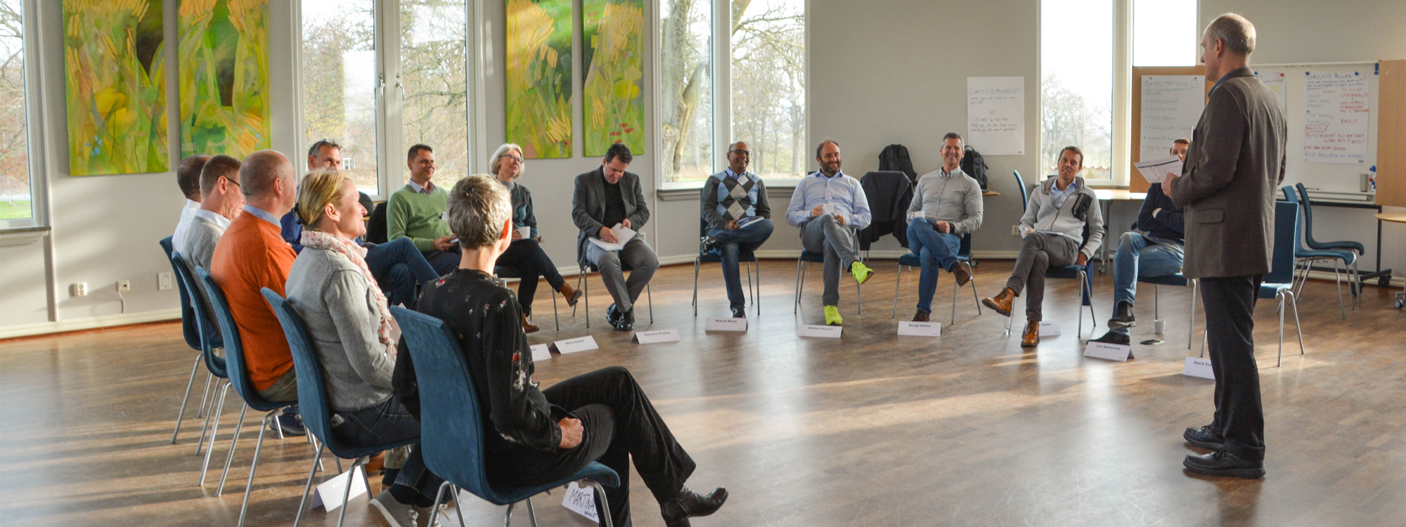 Konferensgrupp samlade för möte i en konferenslokal med stora fönster.